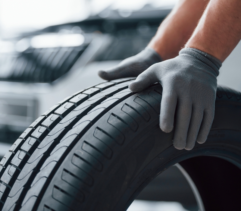 Hands only mechanic holding tire at the repair garage replacement of winter and summer tires.jpg